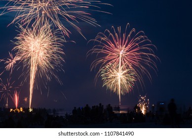 A Crowd Of People Watching Fireworks At The Beach During July 4th Celebrations.