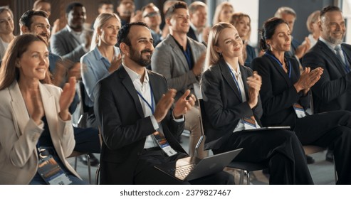 Crowd of Smart Tech People Applauding in Conference Hall During a Motivational Keynote Presentation By Innovative Company. Business Technology Summit Auditorium Room Full of Corporate Delegates. - Powered by Shutterstock