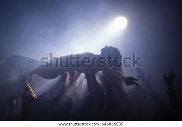 Crowd surfing at a\
concert in nightclub