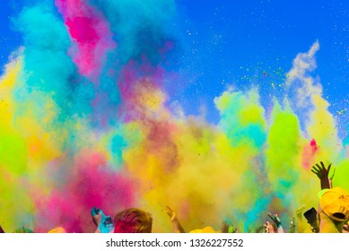 crowd throws colored powder at holi festival