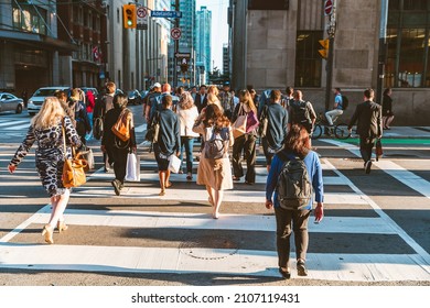 Crowd of unrecognisable people crossing street on traffic light zebra in the city of Toronto at rush hour - Lifestyle in a big city in North America - Shutterstock ID 2107119431