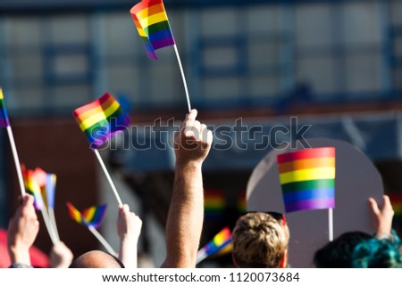 crowd waving rainbow flags at pride parade