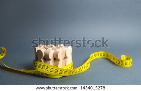 A crowd of wooden figures Gripped by measuring tape. Social Sciences. Promotion of ideas for weight loss, lifestyle. Information statistics, measurement of the number, trends of population growth.