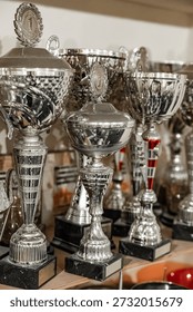 A crowded trophy shelf featuring numerous silver awards, many topped with 