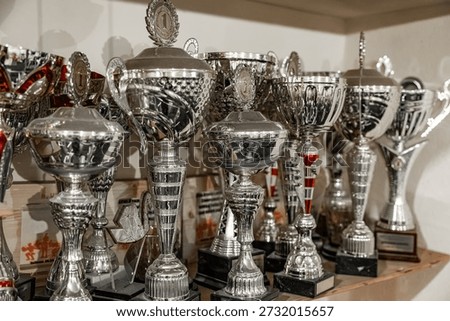 A crowded trophy shelf featuring numerous silver awards, many topped with 