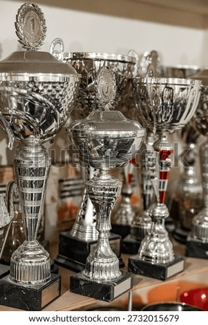 A crowded trophy shelf featuring numerous silver awards, many topped with 
