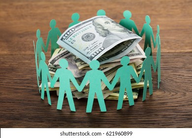 Crowdfunding Concept. Paper Cut Out Human Figures Around The Stack Of Hundred Dollar Bills