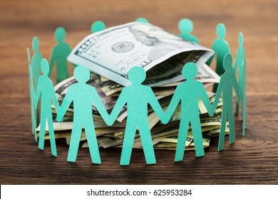 Crowdfunding Concept. Paper Cut Out Human Figures Around The Stack Of Hundred Dollar Bills