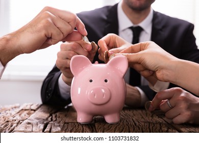 Crowdfunding Concept. People Inserting coins into piggybank