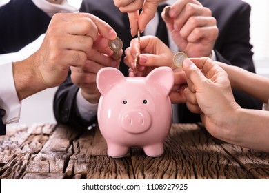 Crowdfunding Concept. People Inserting coins into piggybank