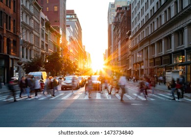 Crowds Of Busy People Walking Through The Intersection Of 5th Avenue And 23rd Street In Manhattan, New York City With Bright Sunset Background