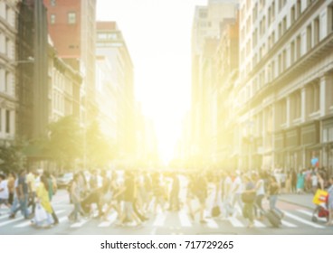 Crowds Of People Crossing A Busy Street In New York City With The Light Of The Bright Light Of The Sun Glowing In The Blurred Background