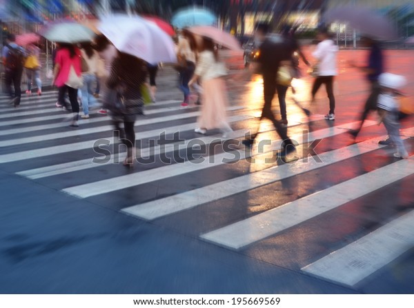 crowds of people crossing the street on a rainy day in\
the city 