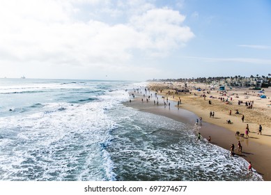 Crowds of tourists and sun bathers having fun and swimming at Huntington Beach. California