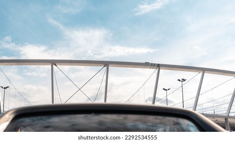 The crown of the football stadium in the background. Blurred windshield of a vintage car in the foreground. Blue sky in the background. Chorzow, Poland - Powered by Shutterstock