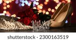 Crown with high-heels, roses and prom dress on dark background with blurred lights