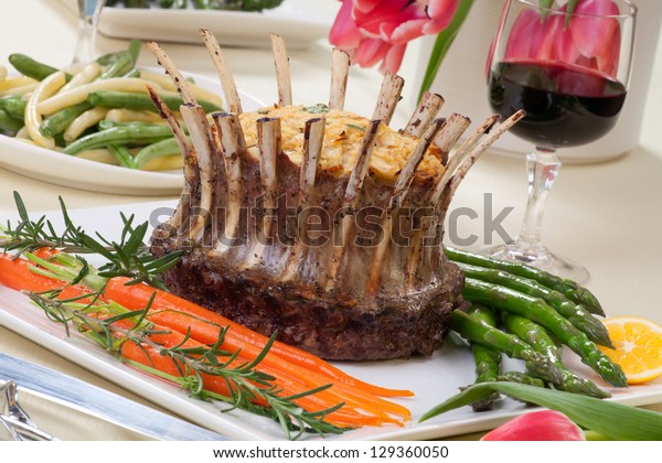 Crown roast of lamb with apple\
rosemary stuffing. Garnished with asparagus, glazed carrots, and\
rosemary twigs. Side dishes - asparagus, and\
beans.