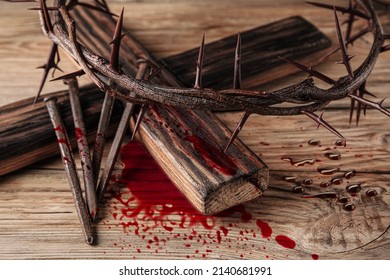 Crown Of Thorns, Cross And Nails Covered With Blood On Wooden Background. Jesus Christ's Sacrifice And Atonement Of Our Sins