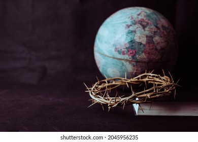 the crown of thorns of Jesus on  the holy bible with blurred world globe on black background against  window light with copy space, can be used for Christian background, Easter concept