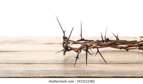 Crown of thorns on wooden table against white background, closeup with space for text. Easter attribute - Shutterstock ID 1913112382
