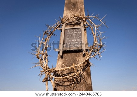 Crown of thorns surrounding plaque of John 1:29 Bible Verse on wooden cross