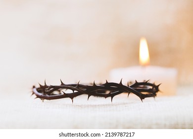 Crown of thorns symbolizing the suffering cross, death and resurrection of Jesus Christ and brightly shining candle background
