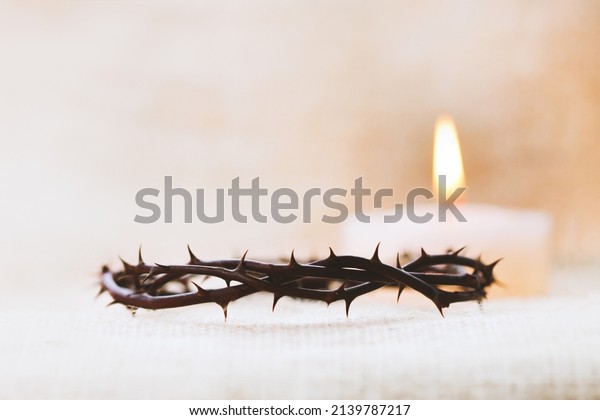Crown of thorns symbolizing the suffering\
cross, death and resurrection of Jesus Christ and brightly shining\
candle background\
