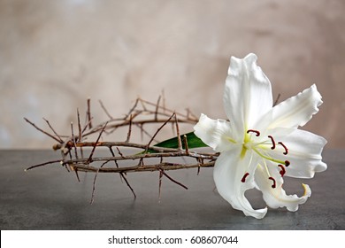 Crown of thorns and white lily on beige background