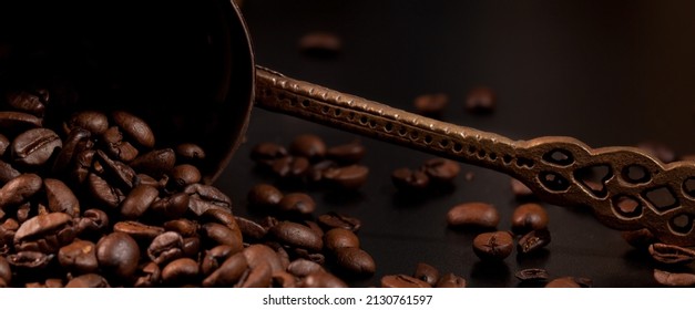 A crucible lying on a black countertop and coffee beans spilling out of it, close-up, detail.