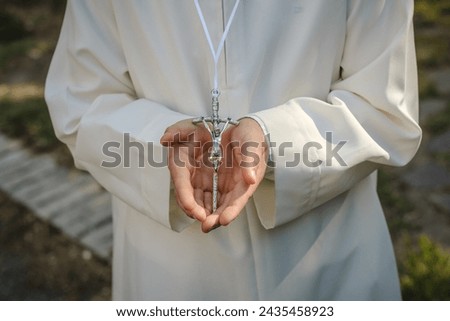 crucified in the hands of a child on the day of his First Communion illuminated by a ray of sunshine