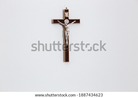 Crucifix of Jesus Christ on white wall in catholic family home. Christian background with copy space. 