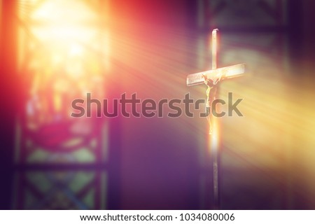 crucifix, jesus on the cross in church with ray of light from stained glass