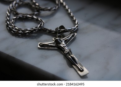 A Crucifix Necklace On A Marble Background.