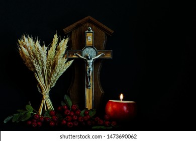 Crucifix (souvenir), rowan branch, wheat ears and burning candle on candlestick in shape of apple on black background. Concept of Christianity, faith, rebirth. Creative idea, imagination and fantasy. - Powered by Shutterstock