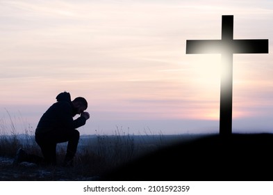 Crucifixion against the sky. Prayer. Repentance. Christian. Clasped hands in prayer. Crucifixion at Calvary. Asks God. Bending his knees at the cross. A man is praying. Easter illustration.