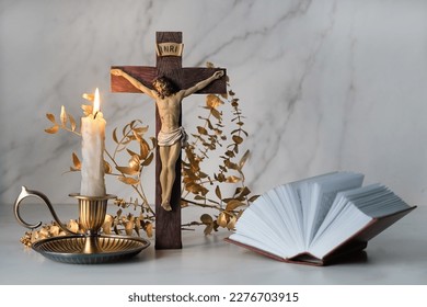 Crucifixion cross, candle and biblical book close up on table. Easter, Orthodox palm Sunday. Good Friday. symbol of Christianity, faith, Lent, prayer. Church religious holiday.