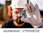 crude nugget of silver stone, manganese or palladium. Mining man holding ore in his hands. Spot focus.