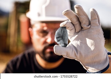 crude nugget of silver stone, manganese or palladium. Mining man holding ore in his hands. Spot focus.