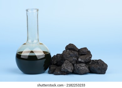 Crude Oil In Glass Beaker And Black Hard Coal Lumps On Blue Background, Fossil Fuel Concept