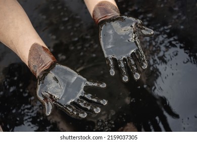 Crude Oil In Hand Due To A Crude Oil Leak. Caucasian Hands Covered With Fuel Oil, In Case Of Oil Spill Environmental Impact. 