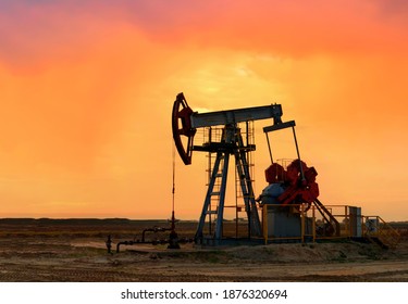 Crude Oil Pump Jack At Oilfield On Atmospheric Sunset Backround. Out Of Focus, Possible Granularity, Motion Blur