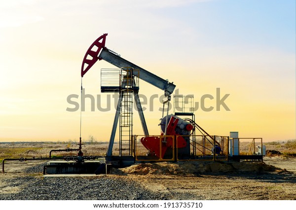 Crude\
oil pump jack at oilfield on sunset backround. Fossil crude output\
and fuels oil production. Oil drill rig and drilling derrick.\
Global crude oil Prices, energy, petroleum\
demand