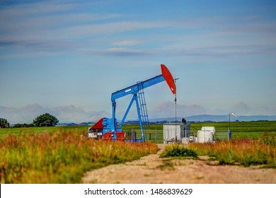 Crude Oil Pump Jack Set Against The Rocky Mountains In Rural Alberta