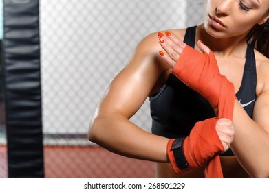 Cruel beauty. Female boxer binding boxing gloves and preparing for training - Powered by Shutterstock