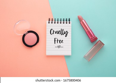 Cruelty free word with lipstick and blush on coral and blue background, flat lay