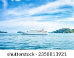 Cruise ship in Andaman sea in Thailand. Seascape with big white passenger liner and green islands, side view. Landscape with boat in marina bay by blue sky background, summer luxury vacations