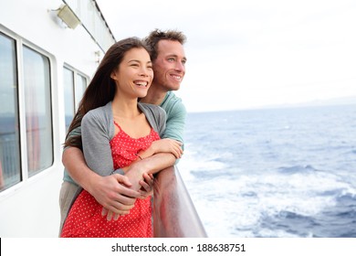 Cruise Ship Couple Romantic Enjoying Travel On Boat Embracing Looking At View. Happy Lovers Traveling On Vacation Sailing On Open Sea Ocean Enjoying Romance. Young Asian Woman And Caucasian Man.