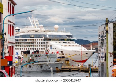 Cruise Ship Moored Next To A Military Ship In The Port Of Ushuaia (Argentina) Seen Between City Buildings