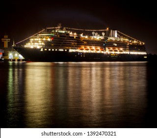 Cruise Ship at night. Large luxury liner docked, Illuminated with lights reflected in the water. All logos removed in Photoshop.