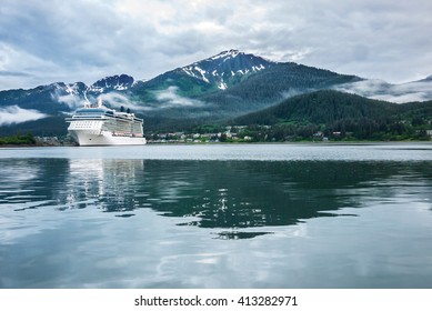 Cruise ship at a port in Juneau, Alaska with snow capped mountain and low lying fog in the background